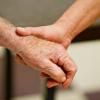 Eine auf Demenzkranke spezialisierte Altenpflegerin hält die Hand eines demenzkranken Mannes.