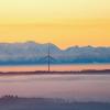 Drei Windräder ragen am Morgen kurz nach Sonnenaufgang aus der Nebeldecke.