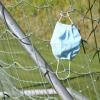 Eine Corona-Schutzmaske hat sich im Tornetz auf einem Fußballplatz verfangen.