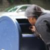 Eine Teilnehmerin der "Smell Tour" schnüffelt ausgiebig in einen blauen Briefkasten hinein.