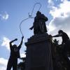 Zwei Männer befestigen ein Seil um den Hals einer Statue von Christopher Columbus.
