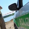 Ein Polizist beobachtet am Sonntag (08.07.2012) am Mittleren Klausensee bei Schwandorf mit einem Fernglas das Gewässer. Ein Spaziergänger will am Samstagabend (07.07.2012) im Schilf des Sees ein Krokodil gesehen haben, wie die Polizei am Sonntag mitteilte