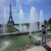 Eine Frau kühlt sich an einem Brunnen im Jardins du Trocadero in der Nähe des Eiffelturms ab.