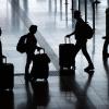 Fluggäste gehen mit Rollkoffern am Flughafen Berlin Brandenburg durch das Terminal 1.