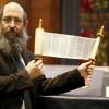 Der Ulmer Rabbiner Shneur Trebnik mit einer Miniatur-Tora. Die verehrte, „echte“ Rolle aus Pergament mit dem handgeschriebenen hebräischen Text wird nur zu religiösen Zwecken aus dem Toraschrein (im Hintergrund) geholt. 