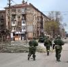 Soldaten der Miliz der "Volksrepublik" Donezk gehen an beschädigten Wohnhäusern in Mariupol vorbei. 