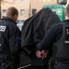 Polizeibeamte führen einen festgenommenen Mann nach einer Razzia in einem Wohnhaus ab. Die Berliner Behörden wollen den Kampf gegen kriminelle Mitglieder arabischstämmiger Clans nun gemeinsam aufnehmen.