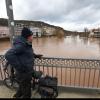 Ein Mann schaut von einer Brücke auf den vom Hochwasser der Fränkischen Saale überschwemmten Kurpark.