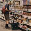 Ein Mann kauft in einem Supermarkt ein. Für den Einkauf müssen die Kunden immer tiefer in die Tasche greifen. 