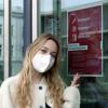 Kommunikationsdesign-Studentin Laura Nachreiner mit Maske vor dem 3G-Schild an der Tür Richtung Mensa.