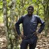 Sougue Moussa steht auf seiner Kakaoplantage neben einem Kakaobaum. 