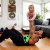 Benny Braun stemmt seine zweijährige Tochter Samira bei den Crunchies für Rücken- und Bauchmuskulatur in die Höhe. 