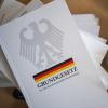 Eine Ausgabe des Grundgesetzes der Bundesrepublik Deutschland liegt auf einem Tisch neben Schreibutensilien. Am 23. Mai wird das Grundgesetz 70 Jahre alt. 