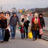 Flüchtlinge, die vor dem Krieg in der Ukraine fliehen, gehen mit ihrem Gepäck eine Straße entlang. Einige Menschen sind in Aichach-Friedberg angekommen. 