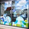 Mit Aufklebern und einem Videomonitor wirbt die Stadt in den Schaufenstern ihrer öffentlichen Büros am Rathausplatz für die Kanu-WM.