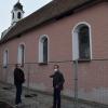 Die Seelenkapelle neben der Wertinger Kirche Sankt Martin ist eingezäunt. Holzelemente im Dachstuhl sind marode, das Mauerwerk ist brüchig. Über die notwendigen Bauarbeiten dort informierte Stadtbaumeister Anton Fink Wertingens Bürgermeister Willy Lehmeier (rechts). 	