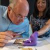 Nicholas Conrad und die Archäologin Keiko Kitagawa schauen sich mit einer Lupe das Fragment eines Entenknochens an.