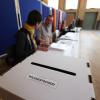 Wahlhelfer sitzen vor einer Wahlurne in einem Wahllokal im Bildungs- und Kulturzentrum Peter Edel in Berlin-Weissensee.