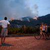 Einheimische beobachten, wie das Feuer am zweiten Tag der Brände in Nago am Gardasee die Vegetation vernichtet.