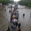 Mehrere Menschen gehen in Mumbai über eine überflutete Straße. Heftige Regenfälle haben Teile der Stadt lahmgelegt.