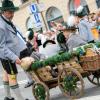 Ein Trachtler im Festzug sieht nach zwei Kindern in einem Holzwagen.