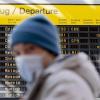 Ein Mann mit Mundschutz steht am Flughafen Berlin-Tegel vor der Anzeigetafel der Abflüge.