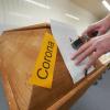 Ein Mitarbeiter des Krematoriums in Dachsenhausen (Rheinland-Pfalz) bringt an einem Sarg die Markierung «Corona» an.