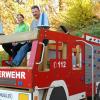 Marina Kuhn, Geschäftsführerin der Regionalentwicklung Landkreis Neu-Ulm, und Ewald Stussak von der Nordholzer Dorfgemeinschaft im neuen „Feuerwehrauto“ auf dem Spielgelände in Nordholz. 