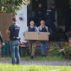 Polizisten schleppen Kisten mit gesicherten Unterlagen aus einem Bauernhof in Bad Grönenbach. 