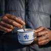 Ein Flüchtling hält eine Tasse mit Kaffee in den Händen. 