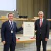 Bürgermeister Florian Mayer (links) verleiht seinem Vorgänger Hans-Dieter Kandler die Altbürgermeisterwürde sowie den goldenen Ehrenring des Marktes Mering.