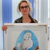 Die Logopädin Sabine Schwab aus Ettringen mit einem Bild der Eule Ulla Hubitz, gemalt von Isabell Beck. 
