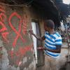 Ein junger Mann malt eine rote Aids-Schleife auf eine Wand im Kibera-Slum und schreibt in roten Buchstaben den Slogan "Avoid AIDS".