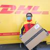 Ein Paketbote mit einer Schutzmaske. Bei DHL können Kunden die Pakete empfangen, ohne selbst unterschreiben zu müssen.