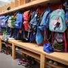 Sporttaschen und Schulranzen hängen an der Garderobe vor einem Klassenzimmer.