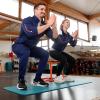 Injoy-Inhaber Walter Seckler und Trainingsleitung Anne Hehl zeigen Kniebeugen. Bei der Übung können Einsteiger sich einen Stuhl zu Hilfe nehmen.
