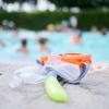 Eine Taucherbrille und Schnorchel liegen in einem Schwimmbad am Beckenrand.