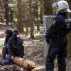 Ein Polizistin im Hambacher Wald vor zwei Umweltaktivisten.