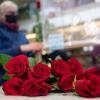 Eine Floristin bereitet in einer Blumenhandlung einen Valentinsstrauß aus roten Rosen vor.