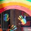 Kinderhände und ein Regenbogen sind an einer Kita zu sehen. Viele Kinder und Familien haben in der Corona-Krise den Regenbogen als Symbol dafür genutzt, dass alles wieder gut wird.