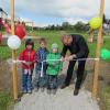 Bürgermeister Robert Wippel durchtrennt zusammen mit den Kindern das Trassenband und eröffnet damit den neuen Spielplatz.