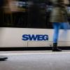 Menschen gehen an einem Zug mit dem Logo der SWEG vorbei.