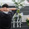 Ein Angehöriger trauert am Freitag (19.08.2011) vor einem Zaun mit Blumen des Pukkelpop-Festivals in Hasselt (Belgien). 