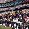 Spieler der New England Patriots knieen während der Nationalhymne auf dem Rasen.