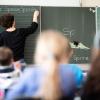 Eine Lehrerin schreibt in einer Schule an die Tafel.