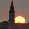 Der 51 Meter hohe Turm der Breitenthaler Kirche vor der untergehenden Sonne.