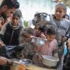 Menschen stehen in Rafah im Süden des Gazastreifens mit Töpfen, Schalen und Tüten bei einer Essensausgabe an.