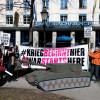 Demonstranten vom Aktionsbündnis "Gegen die Münchner Sicherheitskonferenz" stehen vor Beginn der Konferenz mit Plakaten und einem Panzer aus Pappe vor dem Hotel "Bayerischer Hof".