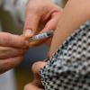Ein Arzt impft eine Frau gegen die Grippe. Kann parallel auch gegen Corona geimpft werden?