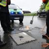 Polizisten versiegeln aus Sicherheitsgründen einen Kanaldeckel an der Protokollstrecke.